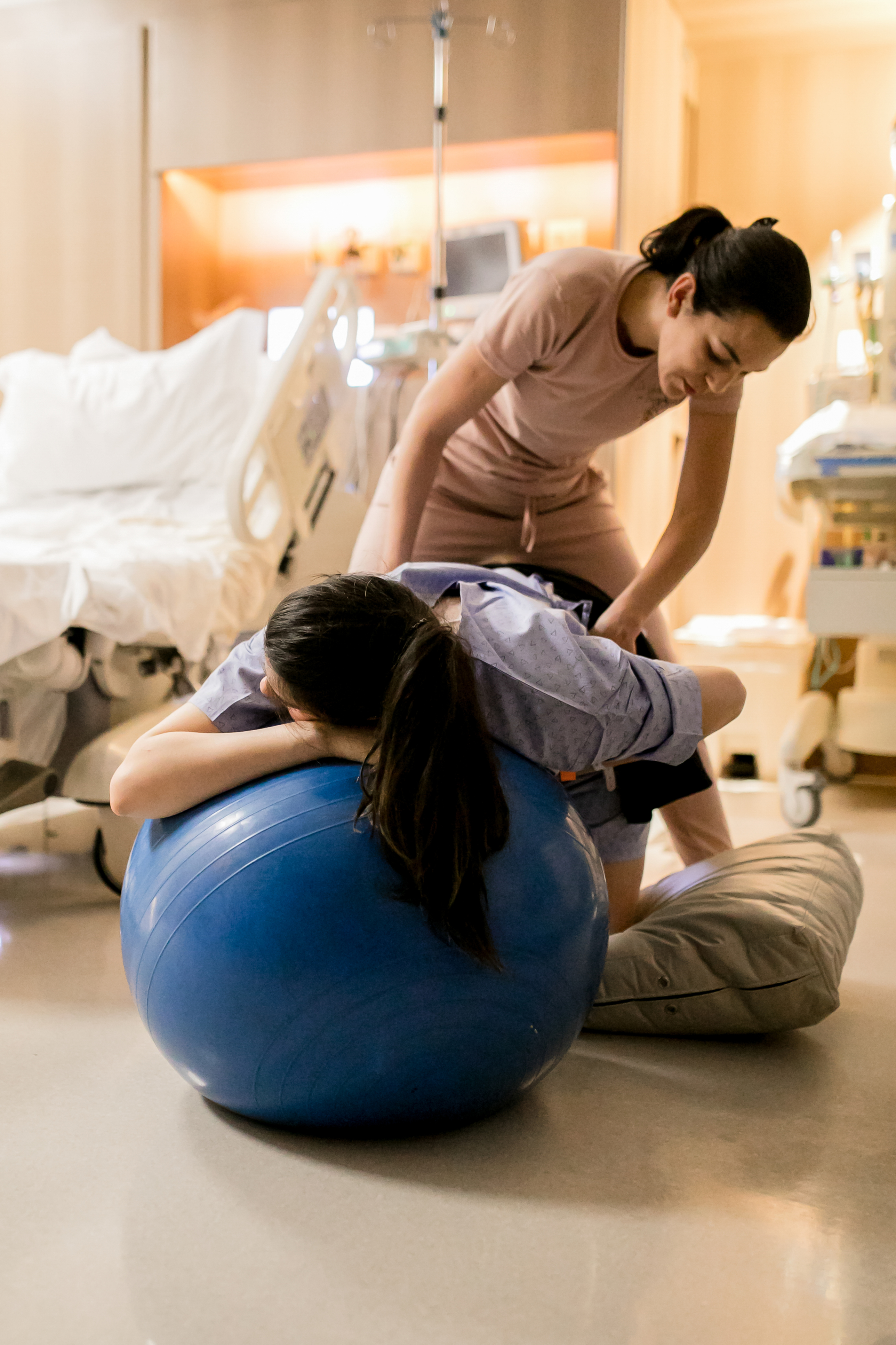 a doula back massaging a pregnant woman who's holding on to her partner