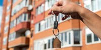 hand holding key with blurred building in background